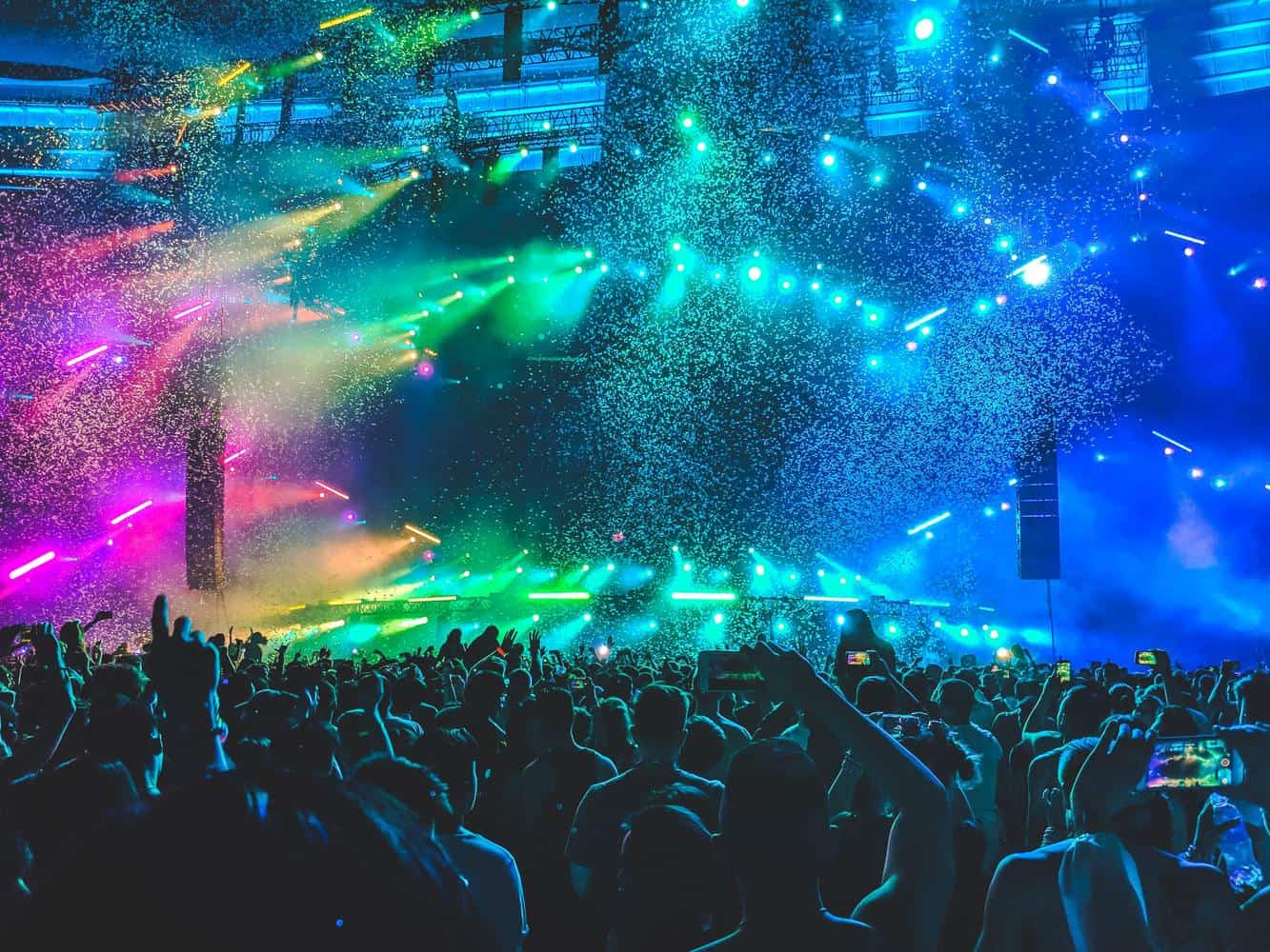 Silent disco event with crowd dancing under bright party lights and stadium-style lasers